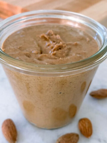 Almond butter in a weck jar with a few almonds near the jar.