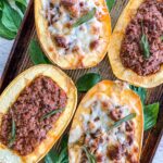 Stuffed Spaghetti Squash with ground beef two of them are topped with melted cheese.