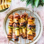 BBQ Pineapple Chicken Kabobs on a plate with grilled pineapple next to it.