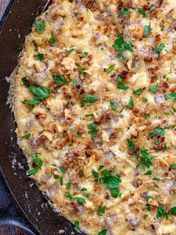 Mac and cheese in a cast iron skillet topped with fresh parsley.