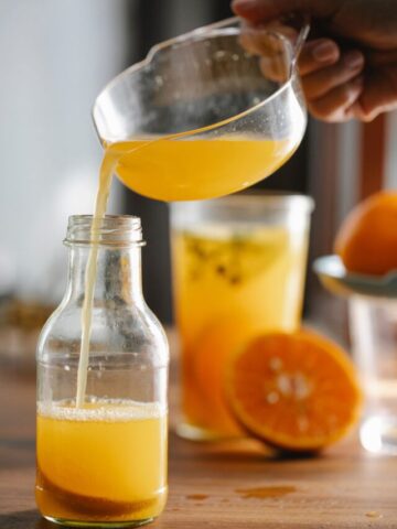 Orange juice being poured into a glass pitcher.