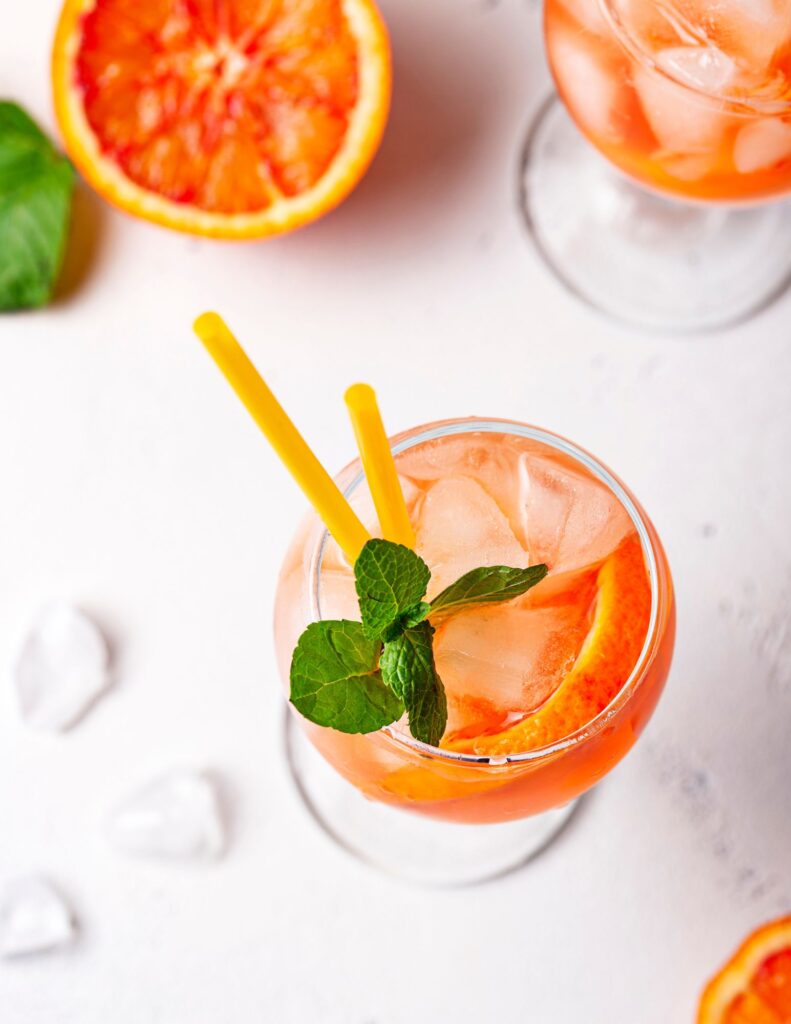 3 Aperol Sodas on a white backdrop with a blood orange on the side.