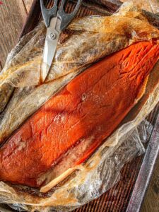 Salmon filet laying on plastic wrap after salmon has brined.