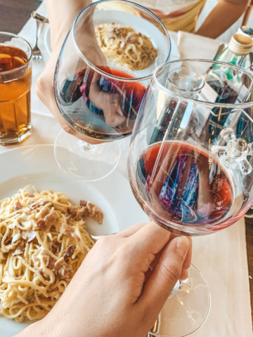 2 glasses of Barolo Wine next to a plate of spaghetti.