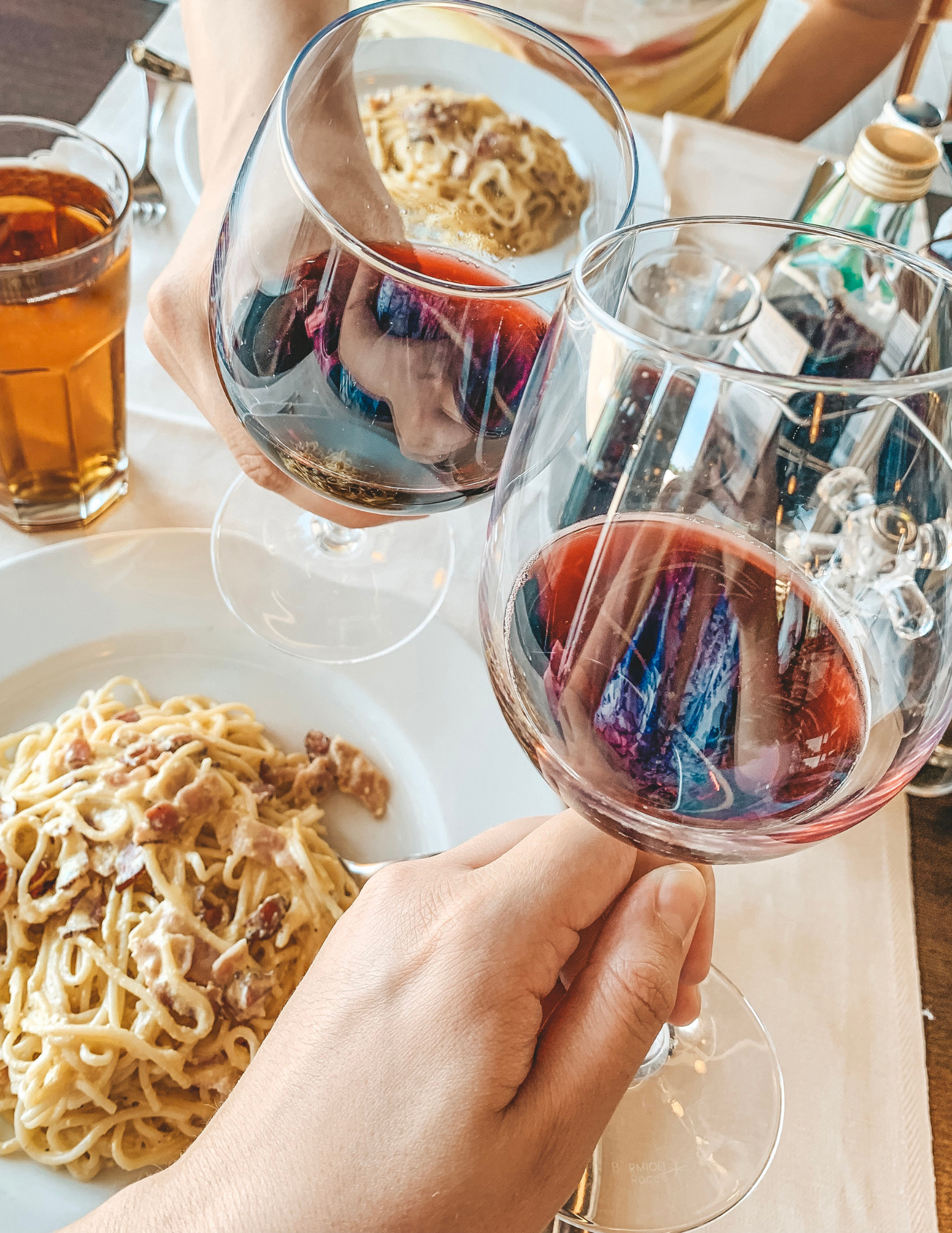 2 glasses of Barolo Wine next to a plate of spaghetti.