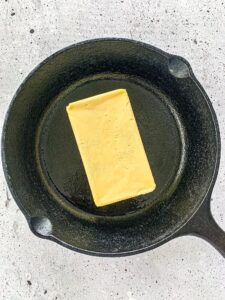 Stick of butter sitting in a cast iron pat.