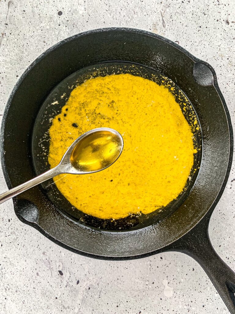 Smoked butter in a cast iron skillet with a silver spoon.