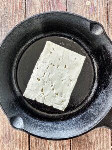 Block of feta cheese in a cast iron skillet.