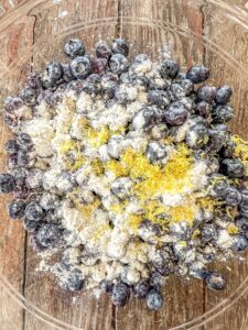 Blueberries in a bowl with gluten-free flour and lemon zest.
