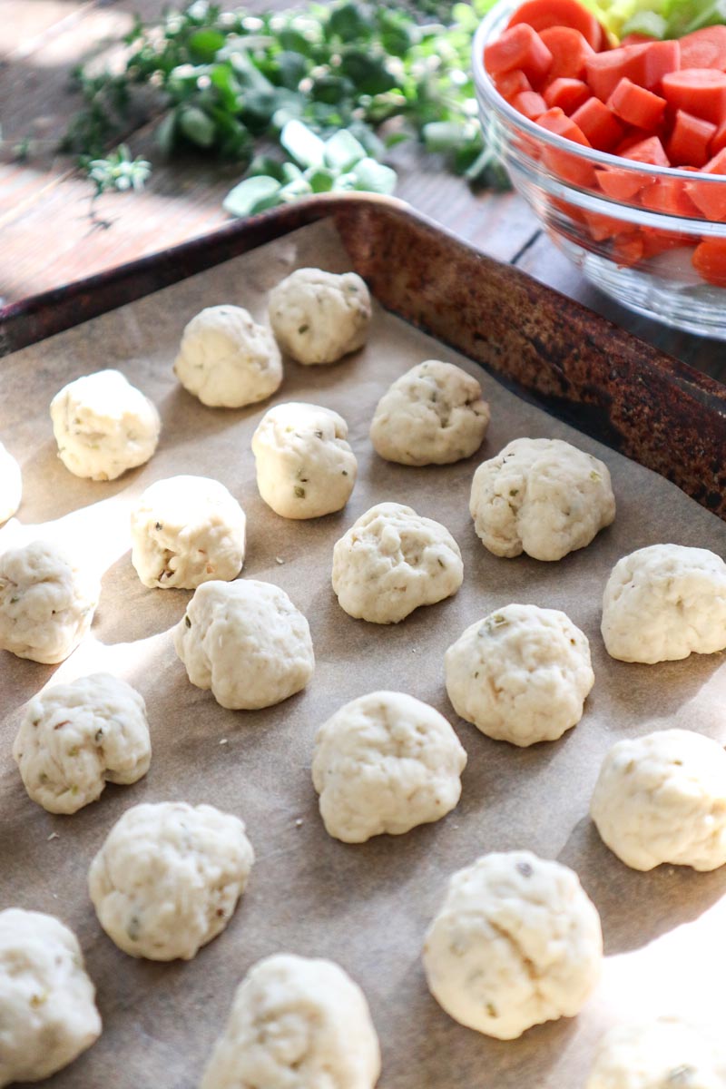 Sourdough dumplings rolled into balls on a baking sheet lined with parchment paper.