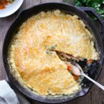 Sourdough Chicken Pot Pie in a cast iron. One slice is missing.
