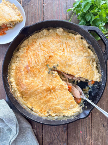 Sourdough Chicken Pot Pie in a cast iron skillet. One slice is missing.