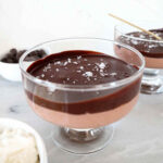 Chocolate cottage cheese mousse in a glass serving dish topped with a hard chocolate shell and sea salt.