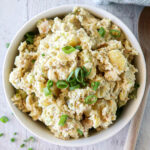 Creamy Potato Salad with spring onions in a white bowl.
