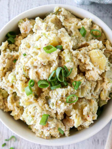 Creamy Potato Salad with spring onions in a white bowl.