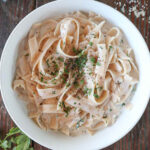 Overhead shot of Cottage Cheese Alfredo on a white plate topped with parsley and black pepper.