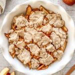 Overhead shot of gluten-free apple cobbler in white pie dish.