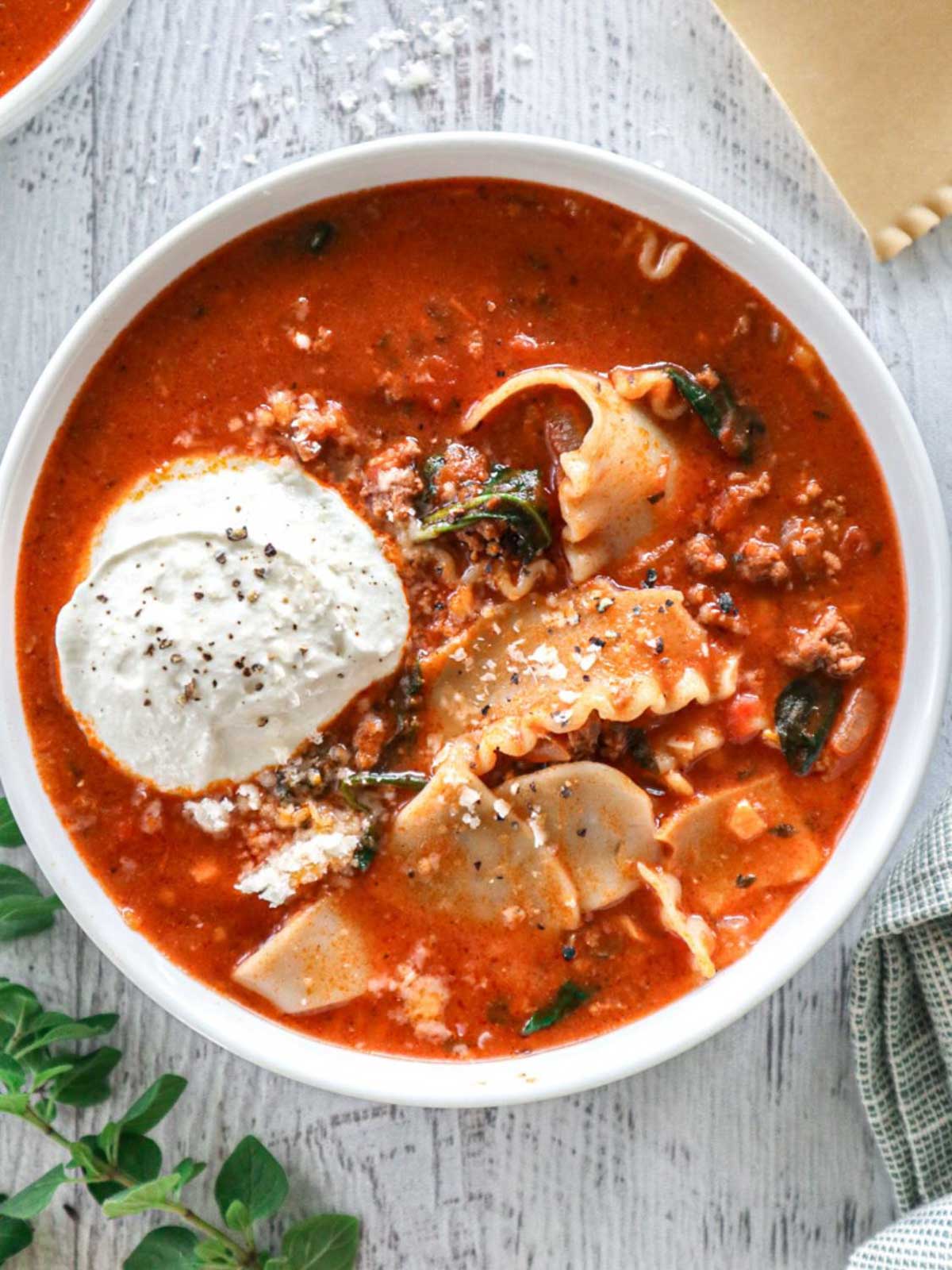 Lasagna Soup in a white bowl topped with whipped cottage cheese.