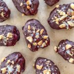 Snickers Stuffed Dates on parchment paper.