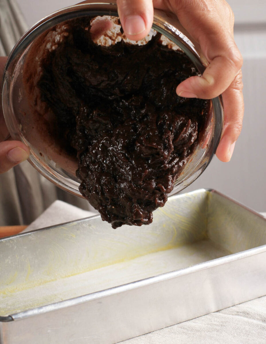 Sourdough brownie batter being poured into a pan.