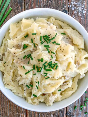 Truffle Mashed Potatoes in a white bowl topped with chives.