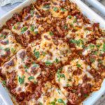 Gluten-free lasagna topped with fresh parsley in a white baking dish.