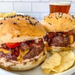 Two smoked burgers on hamburger buns with chips.
