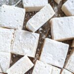 Close-up of several square marshmallows coated in arrowroot powder.