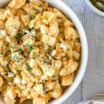 A bowl of creamy dill pickle egg salad in a white bowl.