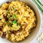 A bowl of creamy saffron mushroom risotto topped with chopped chives.