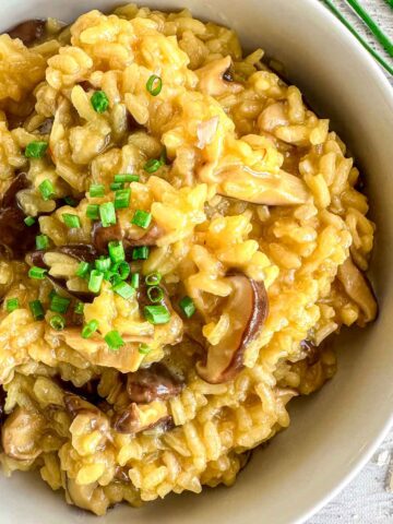 A bowl of creamy saffron mushroom risotto topped with chopped chives.