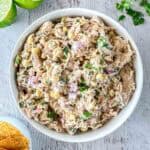 A bowl of creamy Mexican chicken salad with corn, chopped red onions, and fresh herbs.