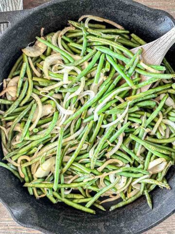 A cast iron skillet filled with smoked green beans.