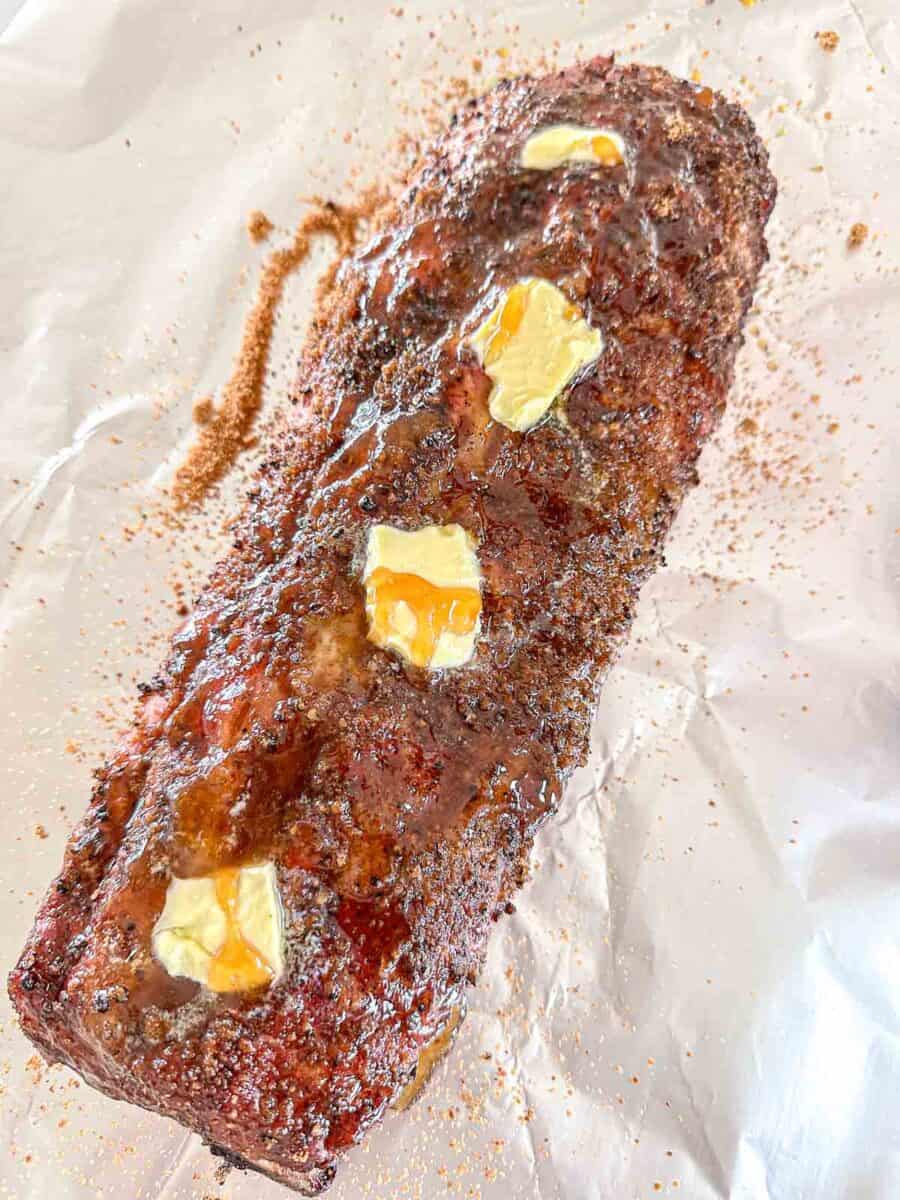 Baby back ribs on foil covered in coconut sugar, butter and hot honey.