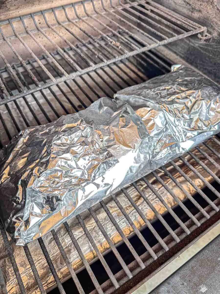 Baby back ribs wrapped in foil on the grill.