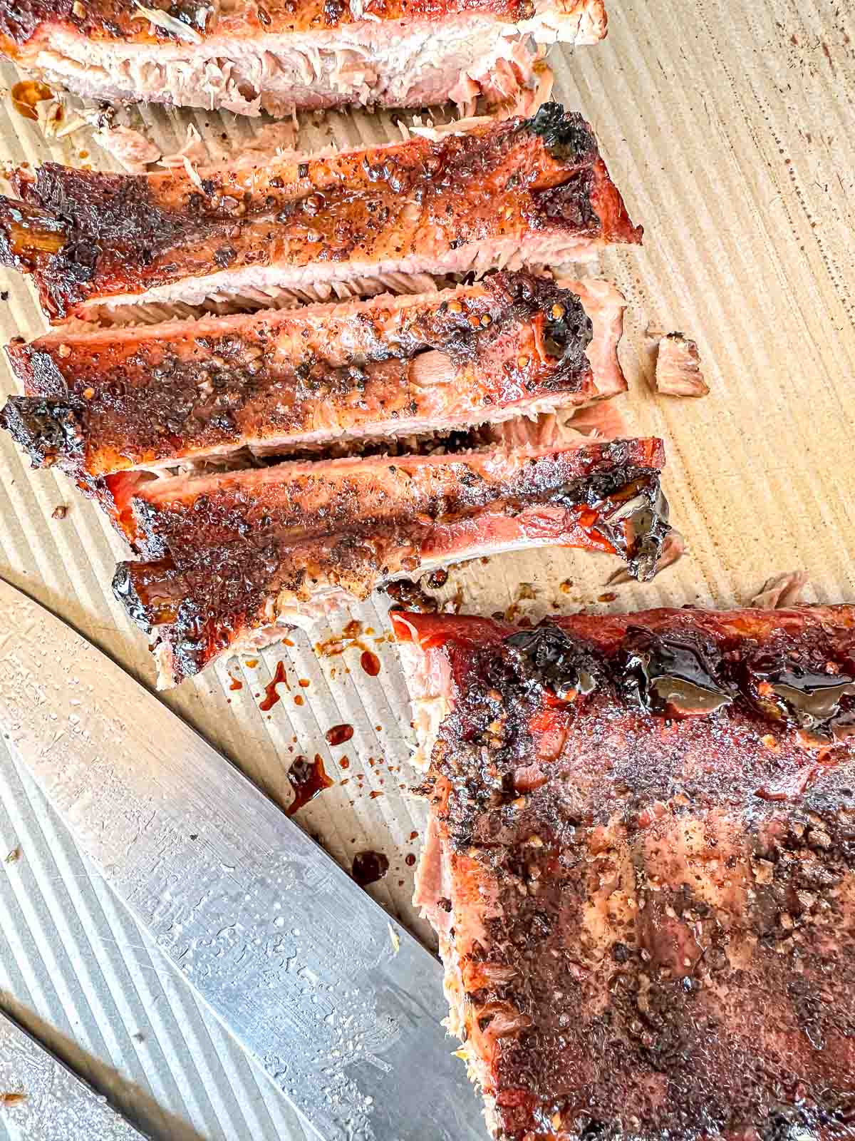 Smoked ribs on a baking sheet some are cut and some are still on the slab.