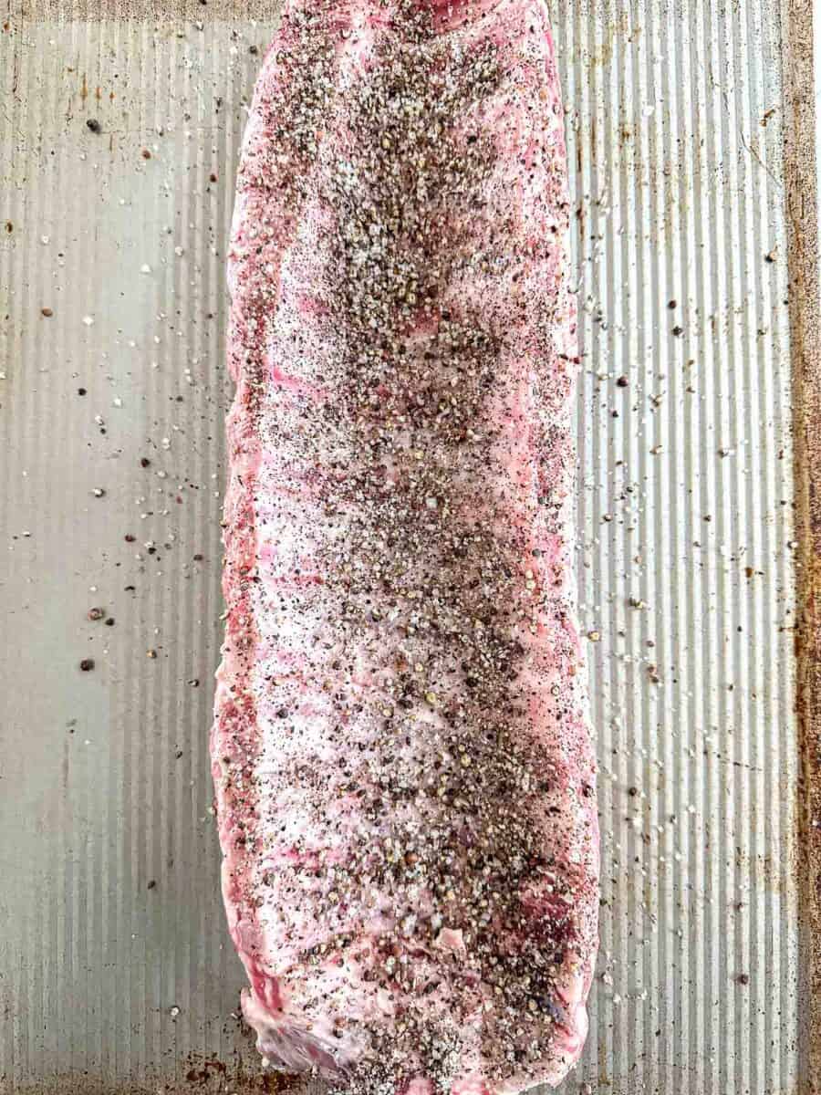 The underside of ribs seasoned with salt and pepper.
