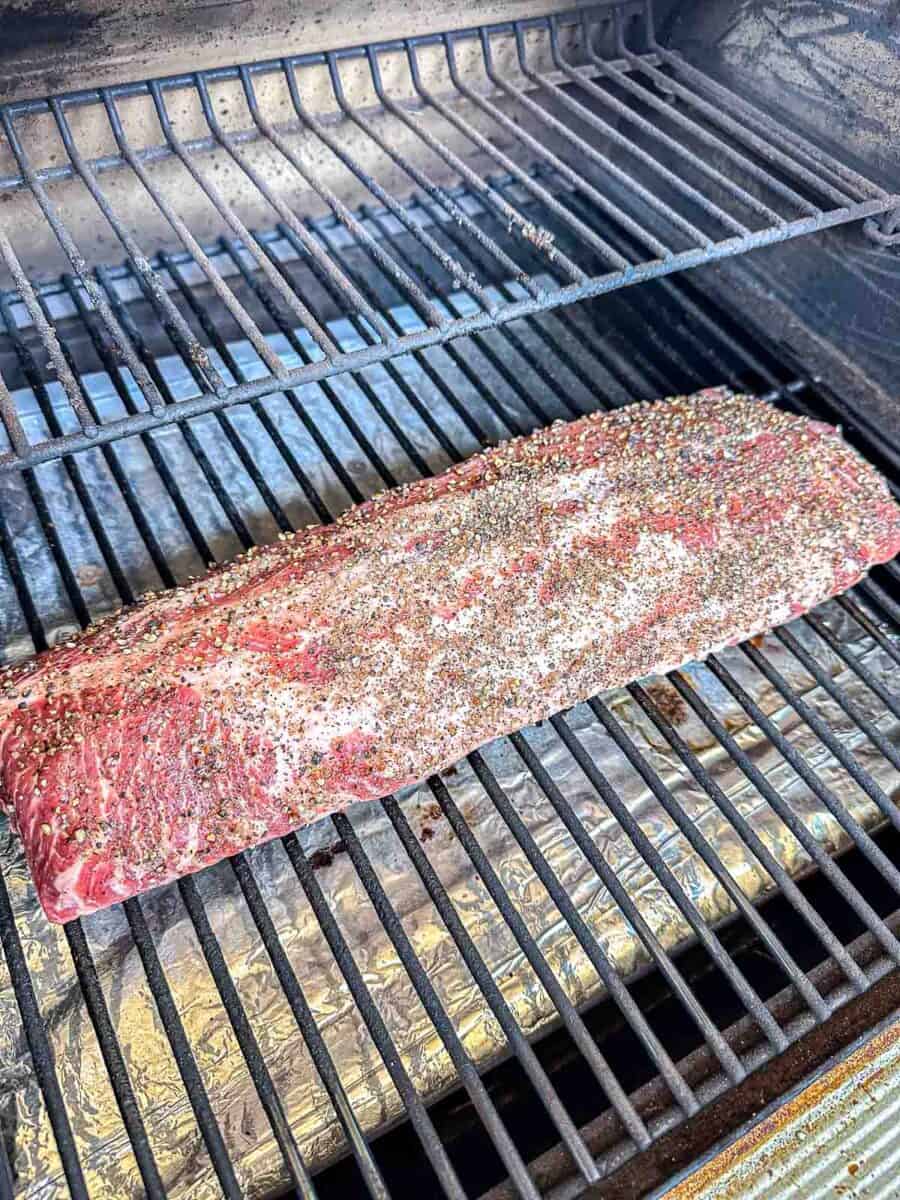Baby back ribs sitting on the grill grates of a Traeger grill.