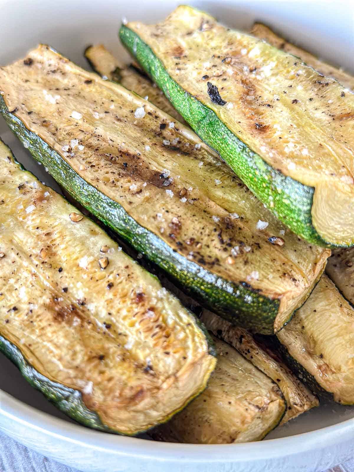 Smoked zucchini slices in a white bowl.