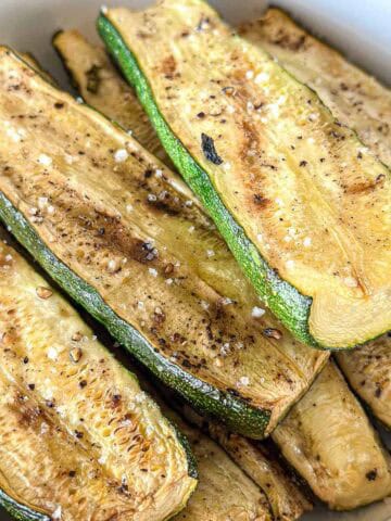 Smoked zucchini slices in a white bowl.