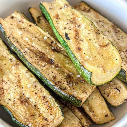 Smoked zucchini slices in a white bowl.