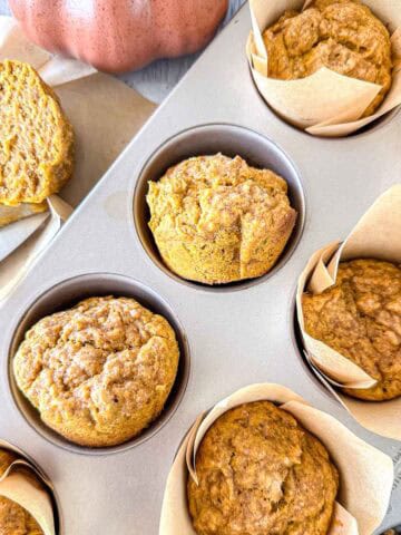 Pumpkin sourdough muffins in a muffin tin.