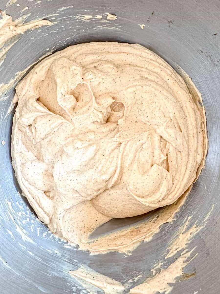 Mixing bowl filled with pumpkin pie cheesecake filling and whipped cream folded in.