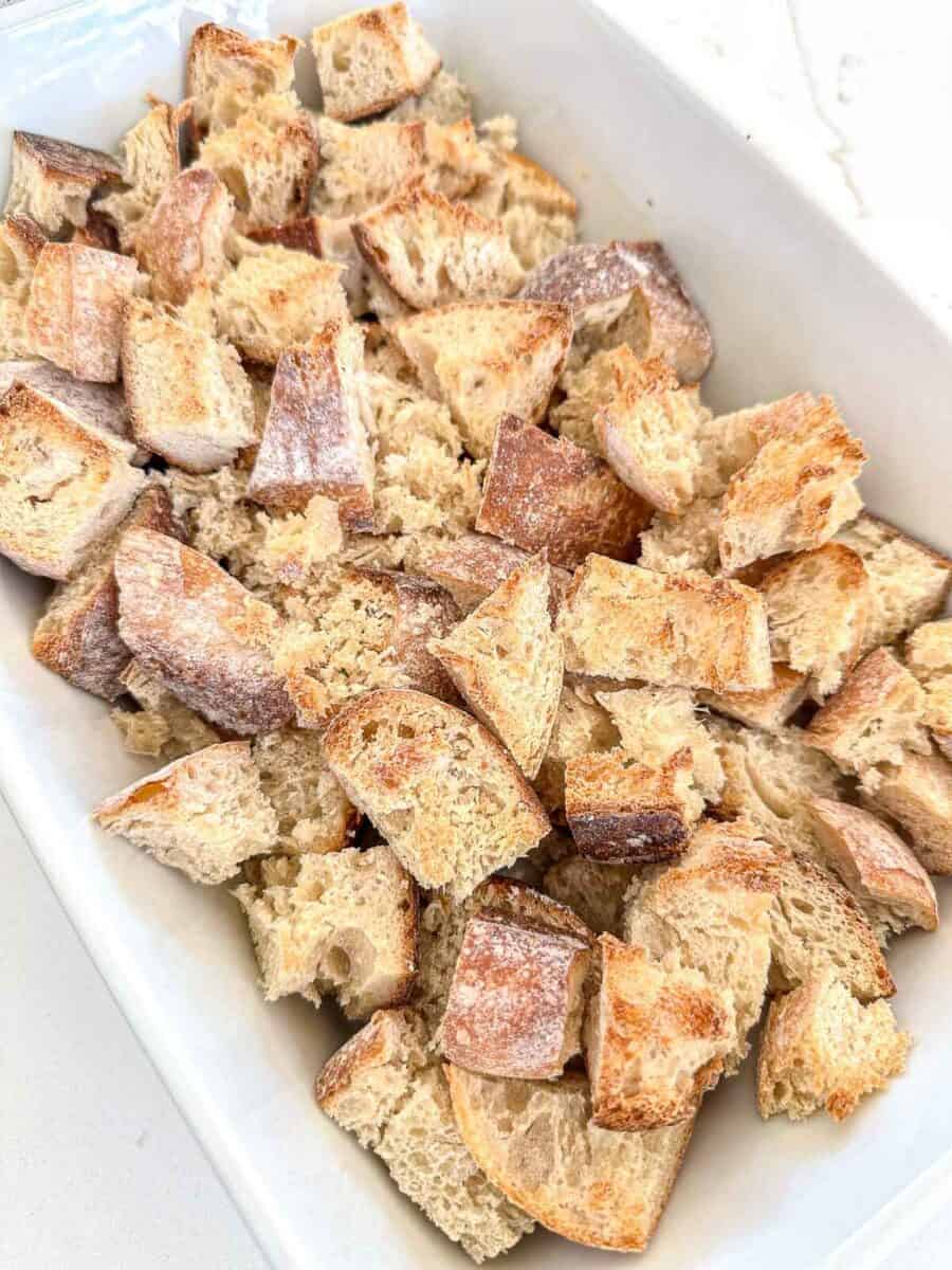 A white dish filled with unevenly cut cubes of rustic sourdough bread.
