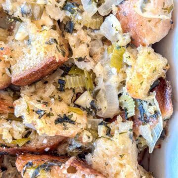 Close-up of homemade bread stuffing with crispy bread cubes, chopped celery, onions, and herbs, showing a mix of golden-brown and soft textures.