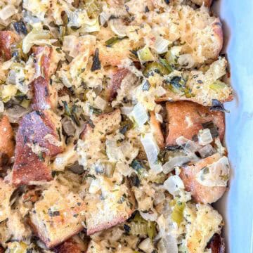 Close-up of homemade bread stuffing with chunks of toasted bread, chopped celery, onions, and herbs, baked until golden and tender in a casserole dish.