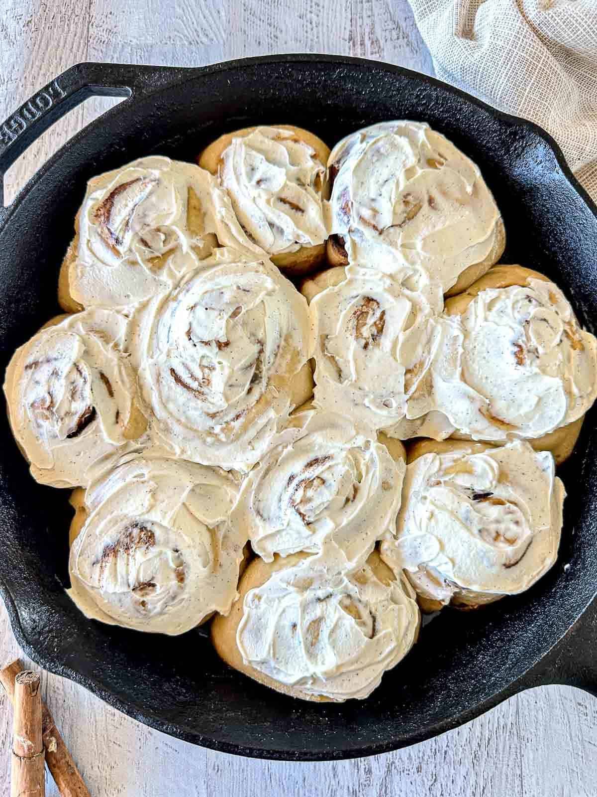 Sourdough Cinnamon rolls topped with labneh cream cheese frosting in a black cast iron skillet.